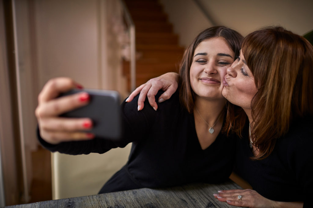 young daughter and her mom smiling and taking a selfie
