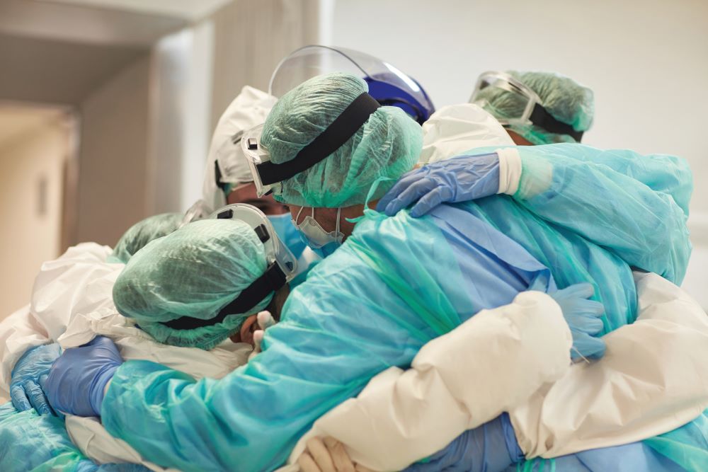 health care workers in a group hug while wearing PPE