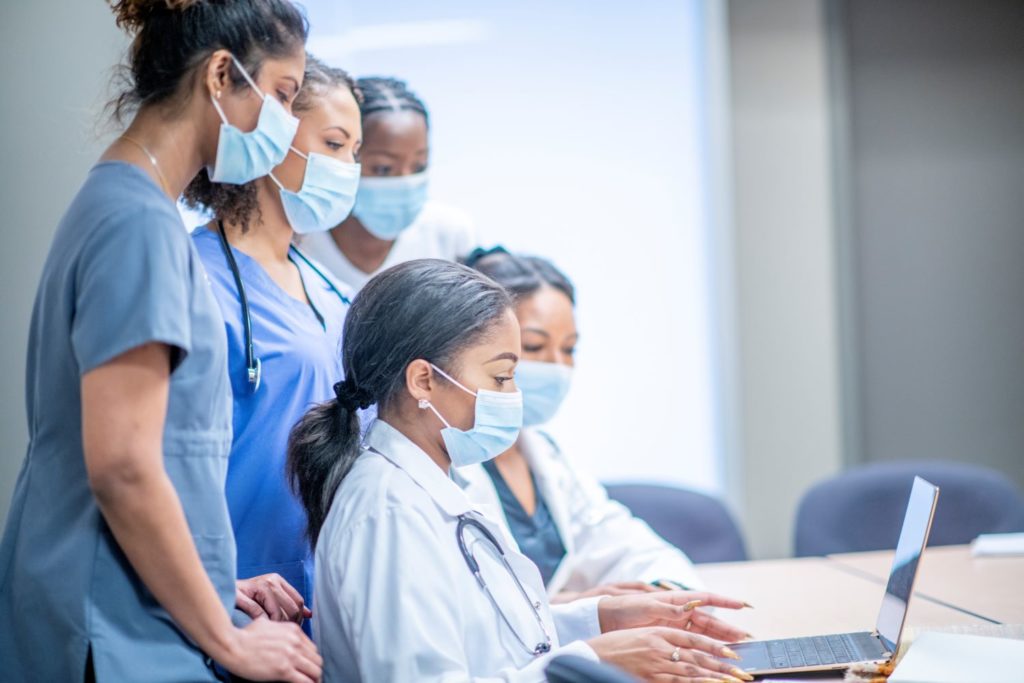 Five health care professionals looking at a laptop