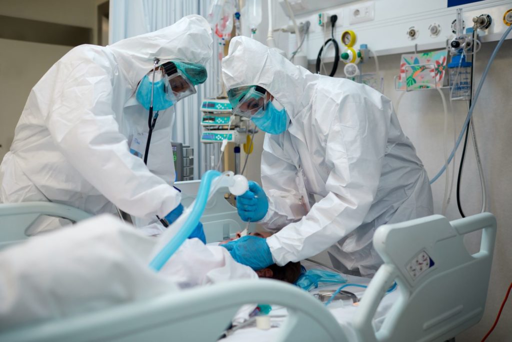 Health care professionals in PPE treating a patient in ICU