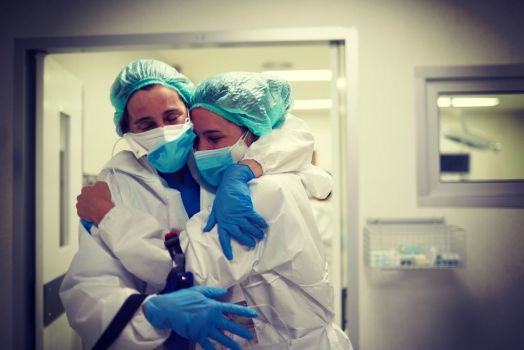 health care workers in PPE hugging