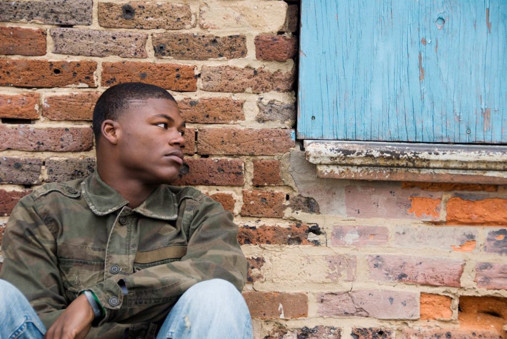Black man sitting in front of brick wall