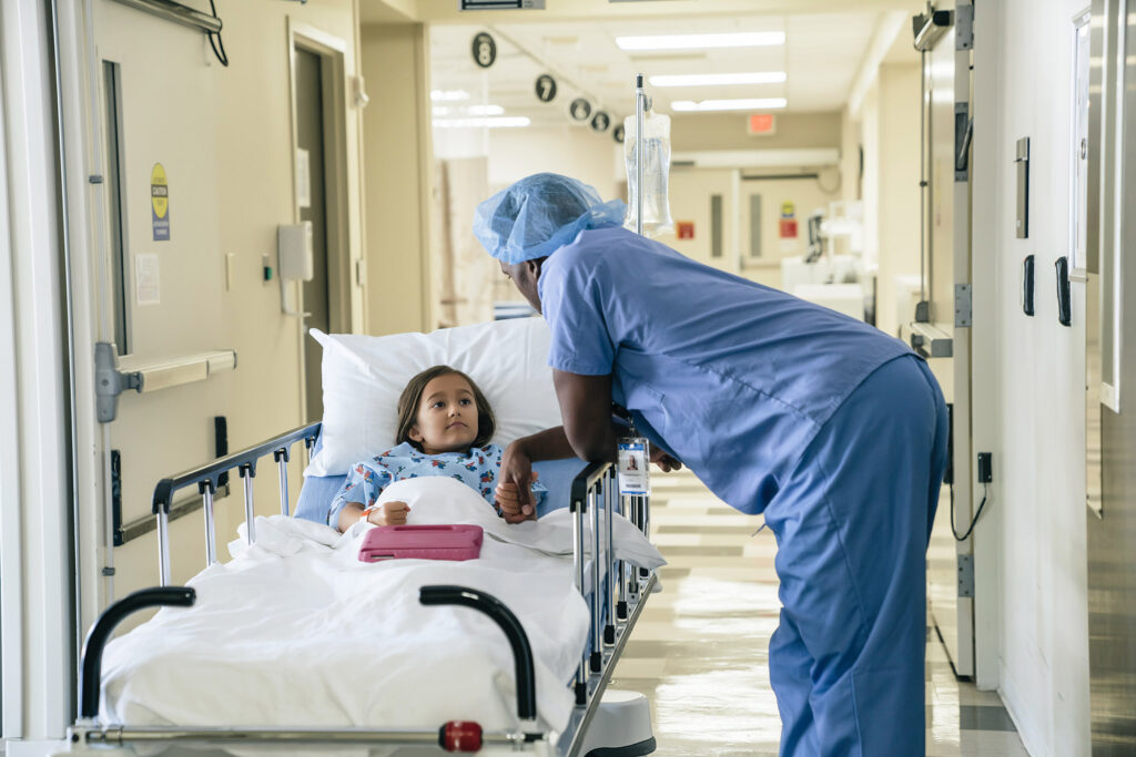 Doctor holding hand of girl in hospital gurney